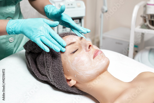 beautician applies face mask to beautiful young woman in Spa salon. cosmetic procedure skin care. Microdermabrasion