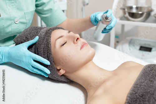 beautician uses facial spray in Spa salon. cosmetic procedure skin care.