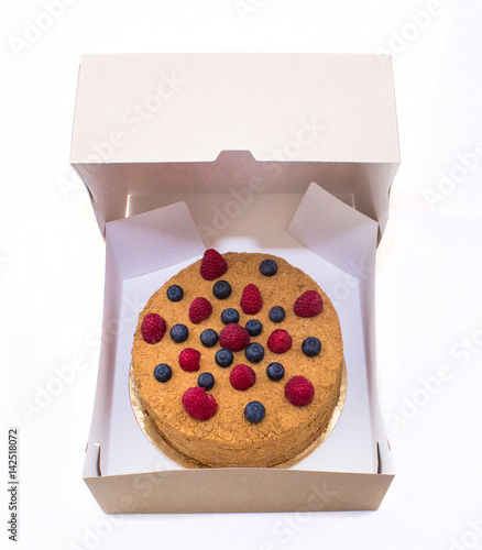 Honey cake decorated with raspberries and blueberries in the packaging and insulation