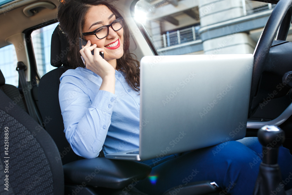 Beautiful young business woman using laptop and phone in the car. Beautiful young business woman using laptop and phone in the car.