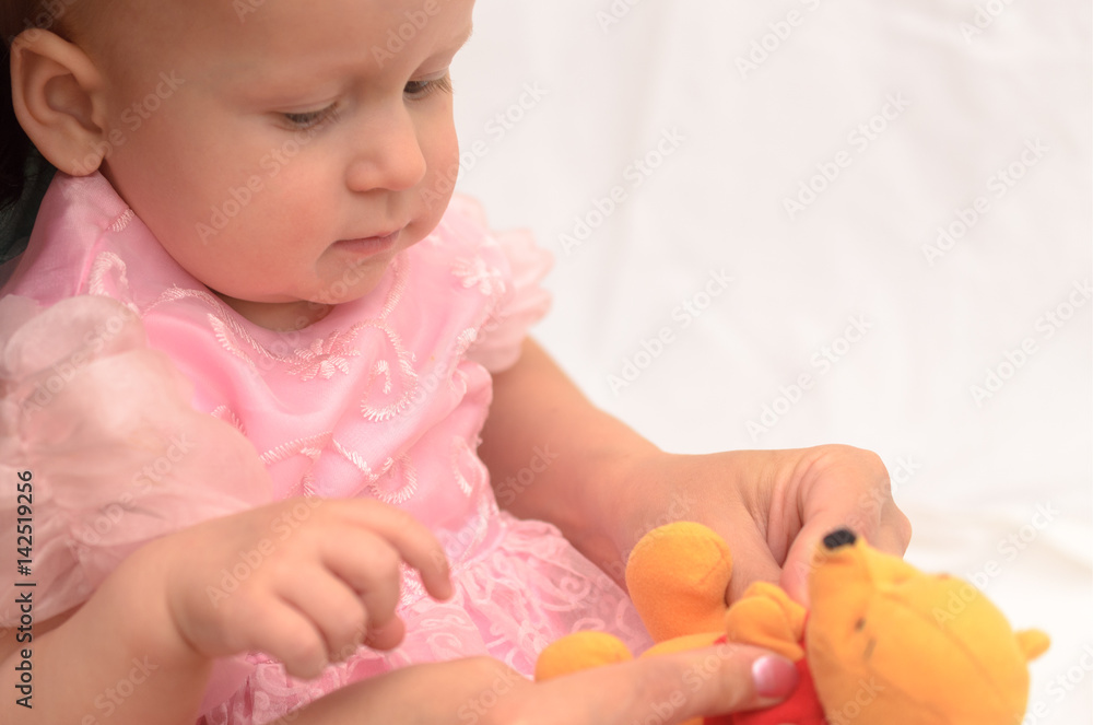 A one-year-old girl with her mother and with a toy.