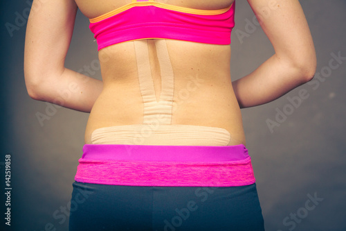 Woman with medical kinesio taping on back