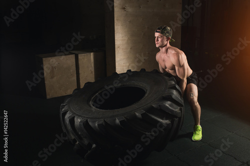 Young man flipping tire at gym photo