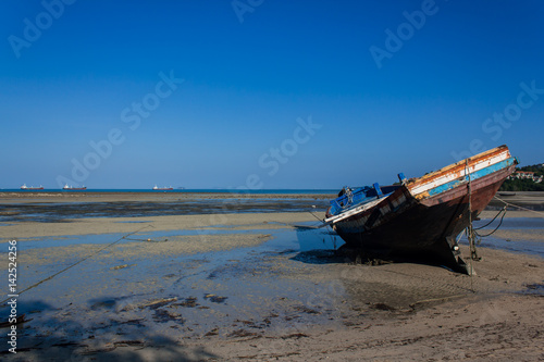 Old ship in shallow water. Old rusty ship in shallow water of ocean with clear blue sky on background.