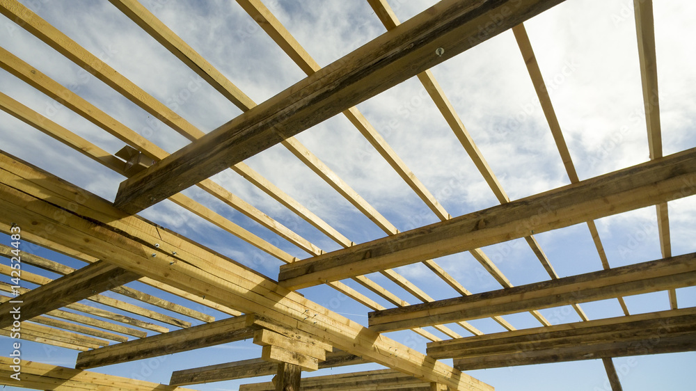 Installation of wooden beams at construction the roof truss system of the frame house Installation of wooden beams at construction the roof truss system of the frame house