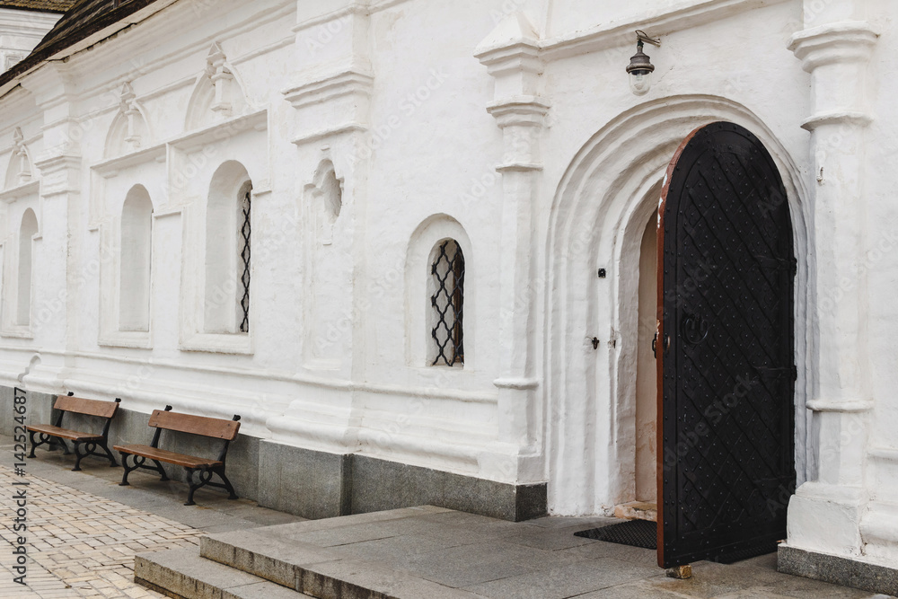 Fototapeta premium Open medieval door with metal decoration in white wall of old orthodox church.