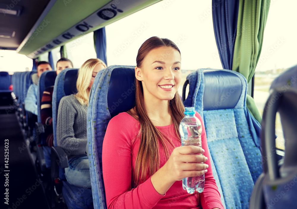 happy young woman with water bottle in travel bus