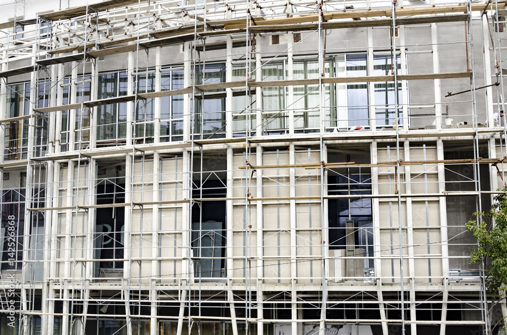 scaffolding a building under construction for external plaster works, high apartment building in city, white wall and window