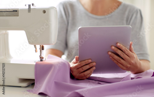 tailor with sewing machine  tablet pc and fabric