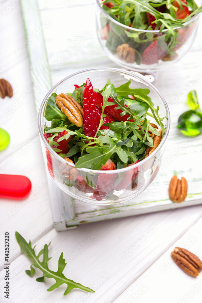 Fresh salad with strawberries, arugula and pecans on a wooden background Fresh salad with strawberries, arugula and pecans on a wooden background