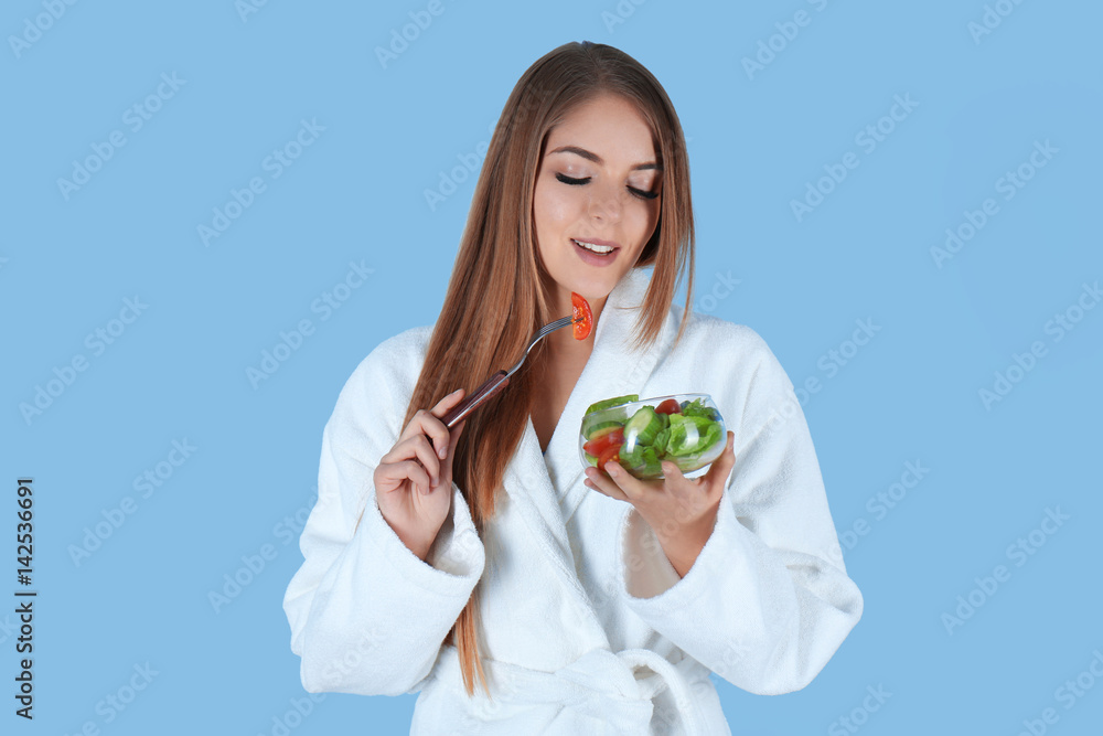 Young beautiful woman eating salad on light background Young beautiful woman eating salad on light background