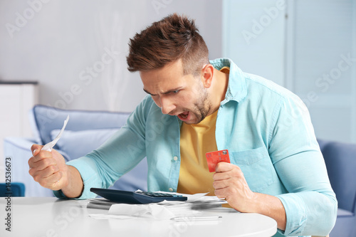 Shocked young man calculati...