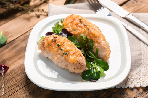 Plate with delicious chicken breasts on wooden table