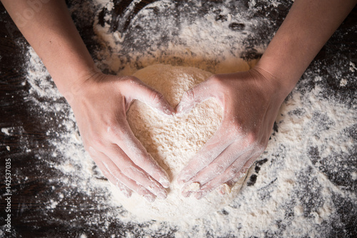 Woomens hands holding finished clean dough in heart shape