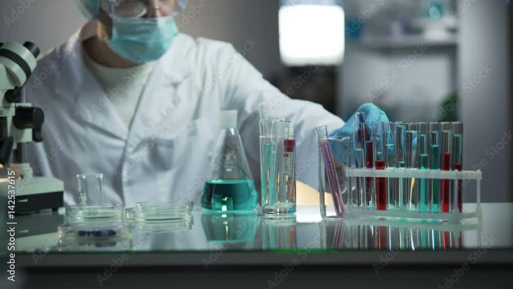 Laboratory assistant examining medical blood sample looking for sediments Laboratory assistant examining medical blood sample looking for sediments