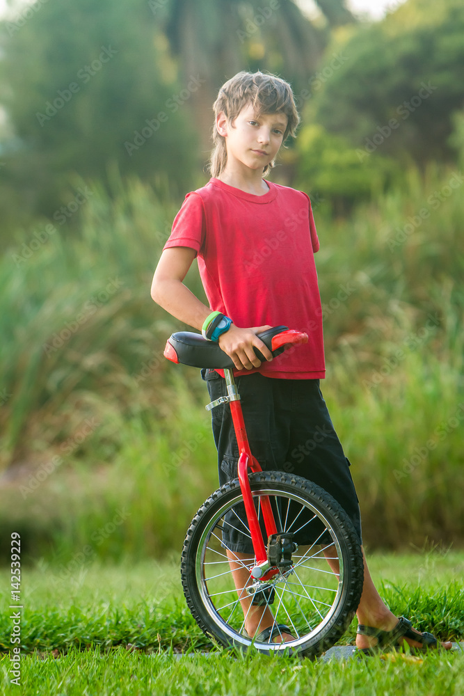 outdoor portrait of young boy riding a unicycle on natural background outdoor portrait of young boy riding a unicycle on natural background