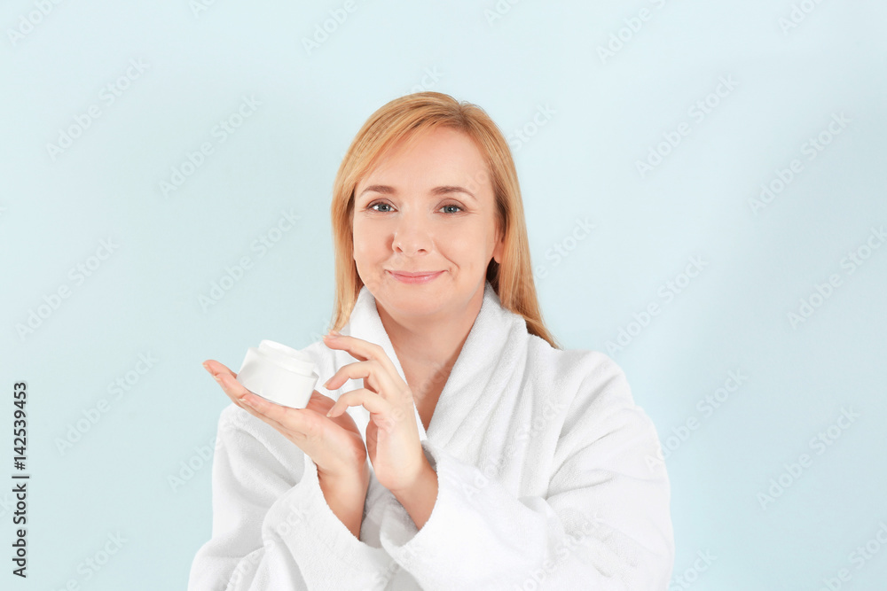 Senior woman applying anti-aging cream on face against light background Senior woman applying anti-aging cream on face against light background