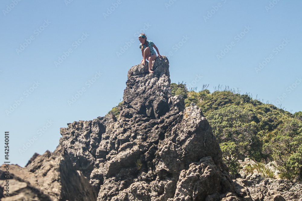 outdoor portrait of young caucasian child girl climbing rocks on beach