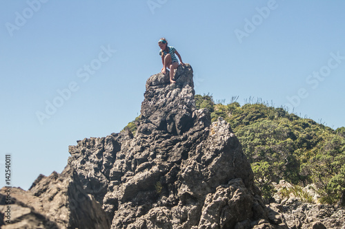 outdoor portrait of young caucasian child girl climbing rocks on beach