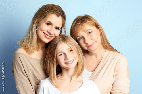 Cute girl with her mother and granny on color background