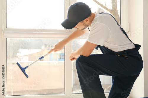 Young man washing window in...