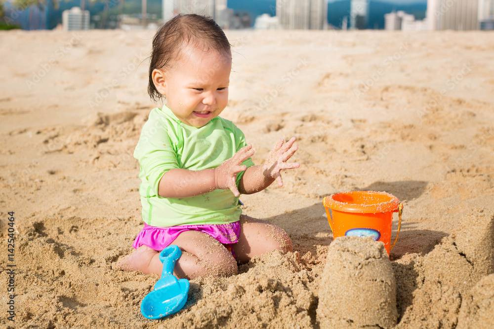 Cutest toddler playing with sand castles at the beach on a sunny summer day. Cutest toddler playing with sand castles at the beach on a sunny summer day.