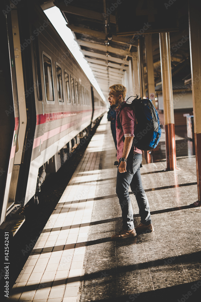 Portrait of a young man traveler waiting for train at platform. Travel concept.