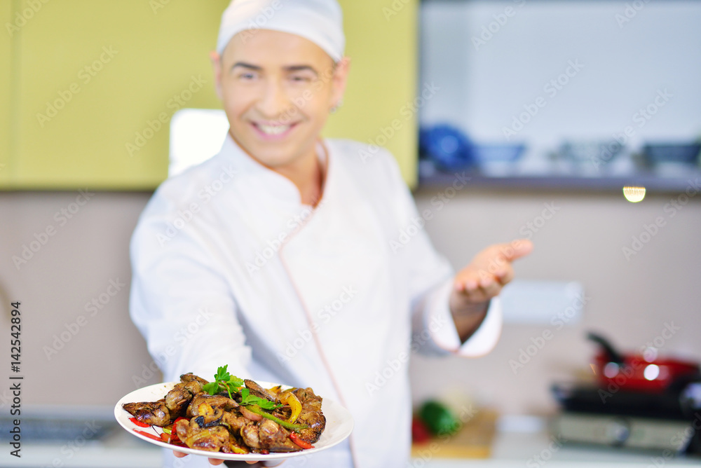 Cook holding plate with food in welcoming gesture