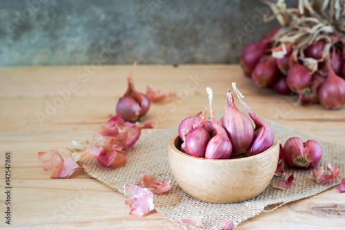 the shallots in bowl on old wooden table with old wallpaper and shallots bunch background