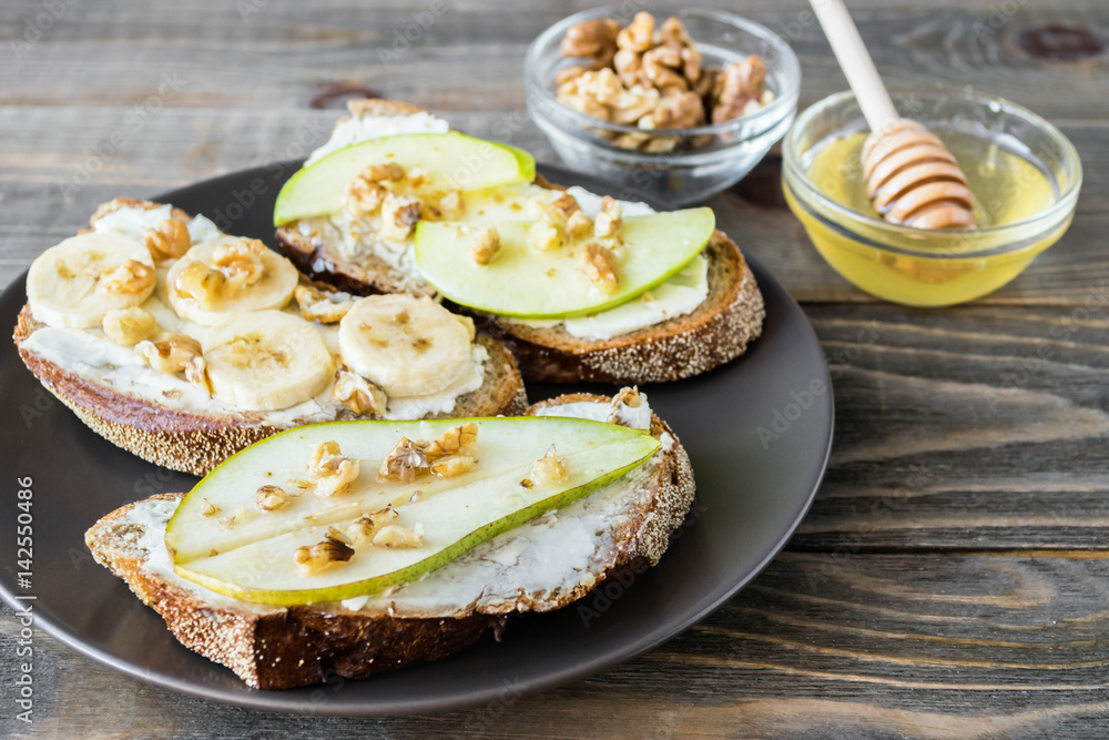 Sandwiches of rye bread and ripe fruit pear banana Apple served on a plate Sandwiches of rye bread and ripe fruit pear banana Apple served on a plate