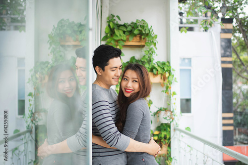 Couple in love sharing genuine emotions and happiness, hugging on the balcony