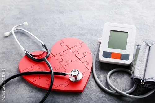 White electric tonometer with stethoscope on grey wooden table photo