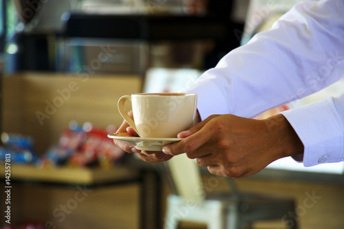 Waiter is serving a cup of coffee