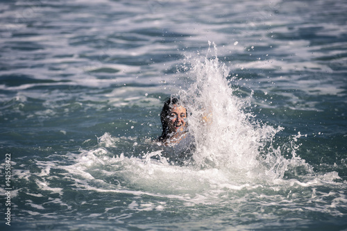 Young and attractive woman is swimming in big waves, Barcelona, Spain