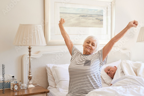 Senior woman waking up with a stretch in the morning 