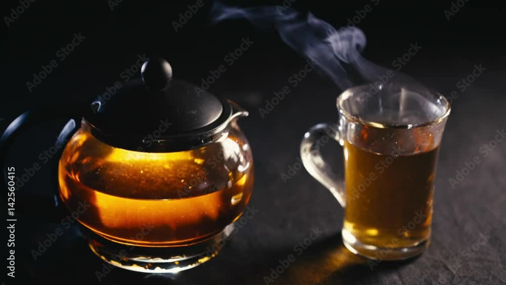 black tea in a transparent teapot tea in glass Cup on black background. black tea in a transparent teapot tea in glass Cup on black background.