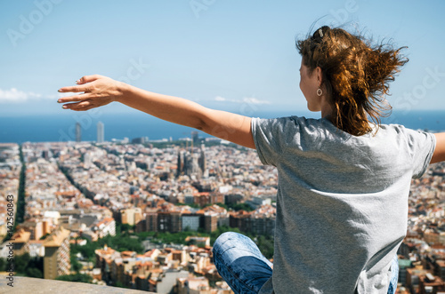 Canvas Print Young happy woman sits back to the camera with raised hands