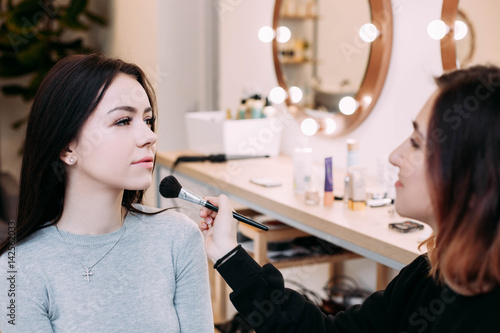 Makeup artist admires her model sitting before the mirror