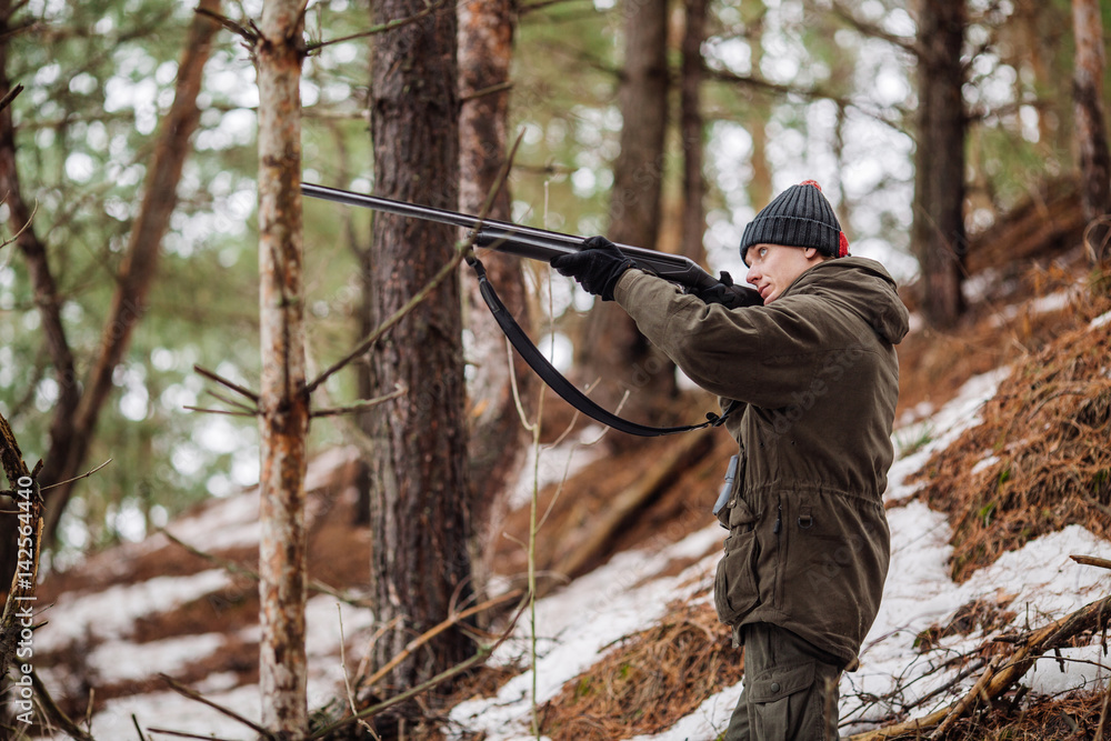 Fototapeta premium male hunter ready to hunt, holding gun and walking in forest.