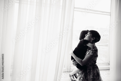Obraz na płótnie The mother with daughter sitting on the window-sill