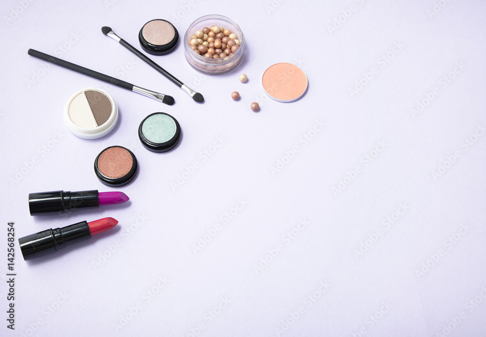 Fototapeta Make up and cosmetic products arranged on a pastel purple background, with empty space at side
