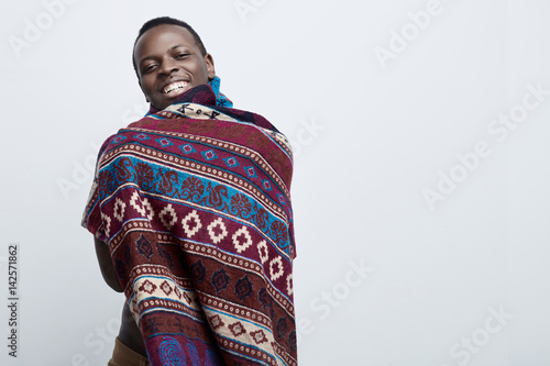 Portrrait of confident young dark-skinned male standing isolated against gray studio wall background with copy space for your text or promotional content, having   friendly cheerful face expression. photo