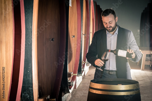 Sommelier tasting red wine in the cellar photo