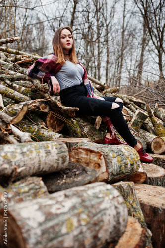 Young hipster girl wear on blanket against wooden stumps on wood.