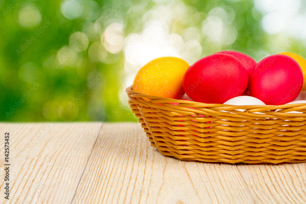 basket with easter eggs on aged table over blurred young foliage with sunbeam basket with easter eggs on aged table over blurred young foliage with sunbeam