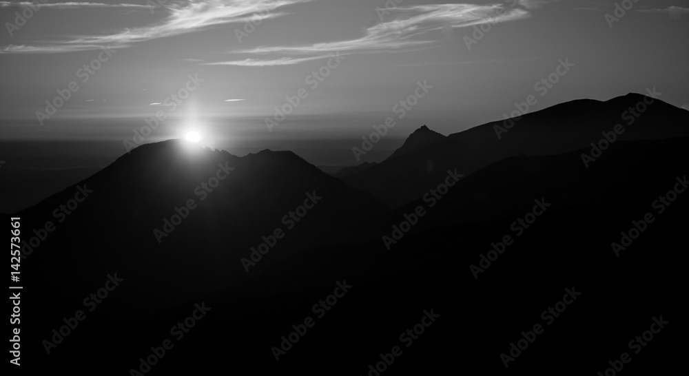A beautiful, abstract monochrome mountain landscape with sun. Decorative, artistic look in black and white style.