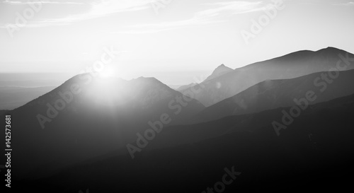 A beautiful, abstract monochrome mountain landscape with sun. Decorative, artistic look in black and white style.