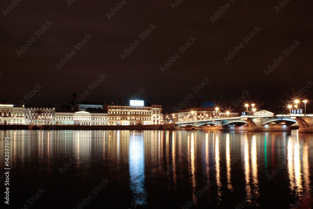 Night long shutter exposure photo of river and relflected lights of buildings and bulbs in Saint Petersburg, Russia