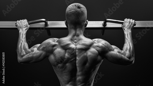 Photos Power muscular bodybuilder guy doing pullups in gym