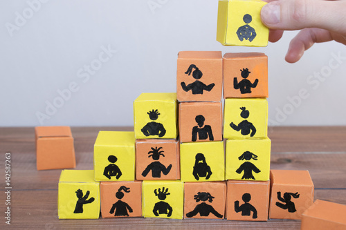 Hiring and team work concept, color cubes with human figures on the brown background. photo